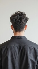 Obraz premium Man facing a white wall showing his curly hair and casual black shirt