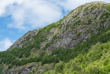 Beautiful Norwegian mountain landscape with a mountain peak against a blue sky. Mountain with green...