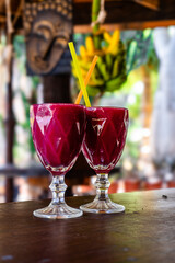 Delicious Prickly Pear Juice in a Clear Glass on Rustic Wooden Table for Healthy Refreshing Drink and Natural Wellness. Bananas in the Background