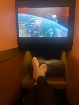 Indulging in premium comfort, a passenger relaxes while watching a movie in Etihad Business Class, enjoying the ultimate in-flight experience with personalized service and entertainment options.