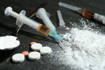 Drug addiction. Powder, pills and syringes on gray table, closeup