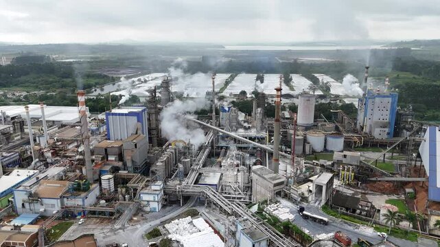 Vis&atilde;o a&eacute;rea de uma ind&uacute;stria de papel e celulose, mostrando as fuma&ccedil;as e poluentes liberados durante o processo de produ&ccedil;&atilde;o. A cena reflete a din&acirc;mica industrial e os impactos ambientais