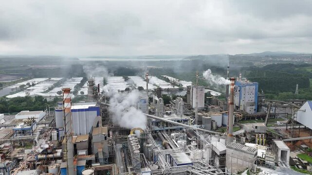 V&iacute;deo em 4k mostrando vis&atilde;o a&eacute;rea nublada de uma ind&uacute;stria de papel e celulose, com chamin&eacute; de caldeira liberando vapor, destacando o processo de produ&ccedil;&atilde;o industrial em um ambiente denso