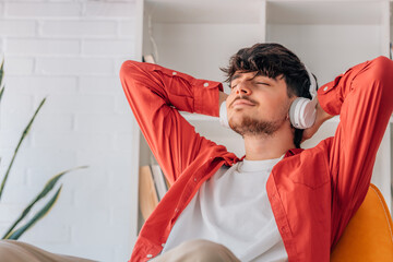 young man at home listening to music relaxing on the sofa at home