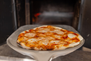 Freshly Baked Pizza Removed from Wood-Fired Oven