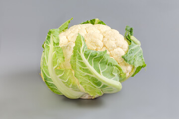 Whole raw cauliflower head on a gray background, front view