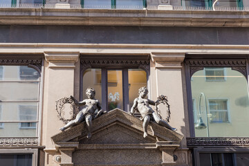 Fragment of historical building facade with angels sculptures on pediment