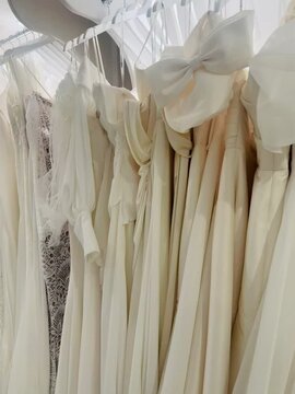 Elegant wedding dresses hanging gracefully on rails in a bridal shop, each one showcasing intricate designs and delicate fabrics, ready for brides-to-be to find their perfect gown.