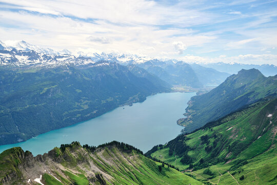 Breathtaking view of Lake Brienz in Switzerland, surrounded by lush green mountains and snow-capped peaks, showcasing the beauty of nature.