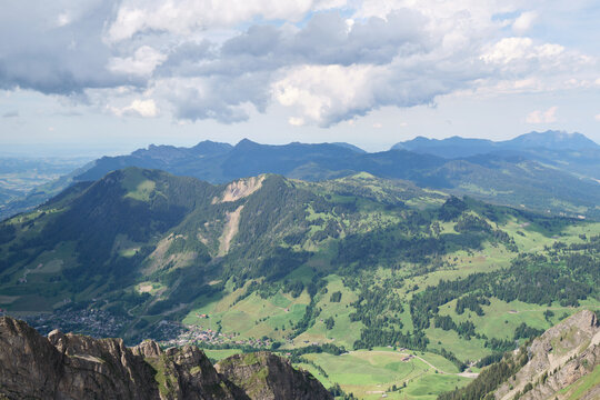 Stunning aerial view of Swiss mountains surrounding Brienz, with lush greenery and dramatic rock formations under a partly cloudy sky. Perfect for nature lovers.