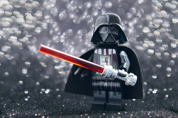Naklejka premium Lego minifigure of Darth Vader from Star Wars with lightning sword isolated on black. Editorial illustrative image of popular plastic constructor.