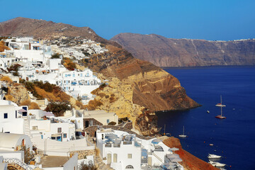 Picturesque view of the traditional white houses on the mountainside in Oia against the backdrop of the sea and Santorini volcano caldera.