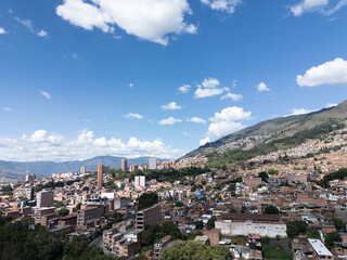 Fototapeta premium Cityscape nestled in mountains under a vibrant blue sky. Buildings climb the hillside, creating a striking contrast. in Medellin Columbia 