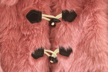 Closeup to fastened front of a pink faux fur coat