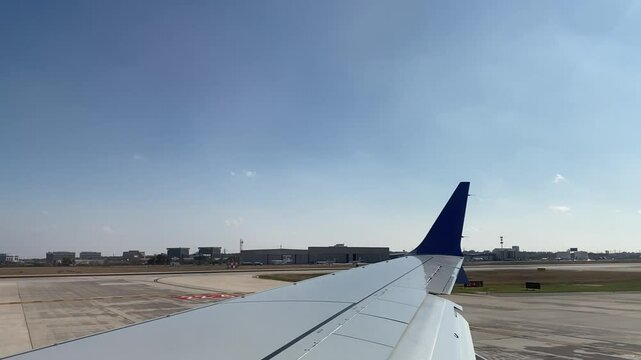 Airplane Wing View During Taxi at Airport on Sunny Day