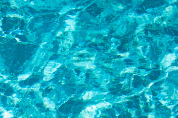 Water background. Blue water, ripples and highlights. Texture of water surface and tiled bottom.