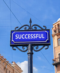 Fototapeta premium Successful symbol. Concept word Successful on beautiful blue road sign. Beautiful blue sky and city building background. Business successful concept. Copy space.