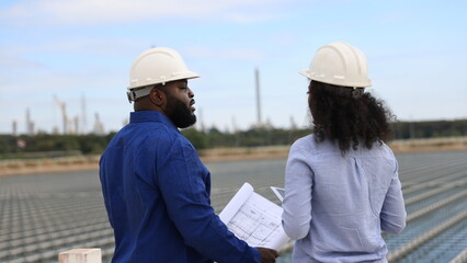 A pair of energy engineers, a man and a woman, are working together to plan the installation of floating solar panels at a specific location.