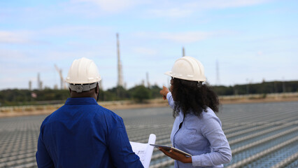 A pair of energy engineers, a man and a woman, are working together to plan the installation of floating solar panels at a specific location.