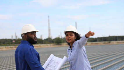 A pair of energy engineers, a man and a woman, are working together to plan the installation of floating solar panels at a specific location.