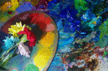 Art palette and fresh flowers on an abstract art background.