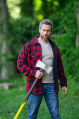 Lumberjack cutting the tree by the axe. Handsome man with an ax in the forest. Handsome man or lumberjack, bearded hipster in checkered shirt with axe. A bearded lumberjack with a large ax.