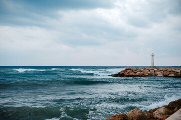 Lighthouse on a Rocky Shore Under Cloudy Skies