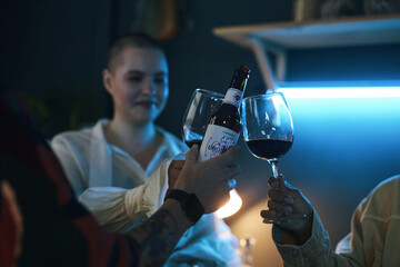Group of friends toasting with glasses of red wine and celebrating holiday together at party