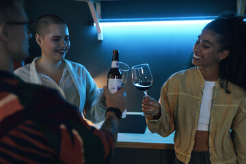 Group of friends drinking red wine and toasting together at party