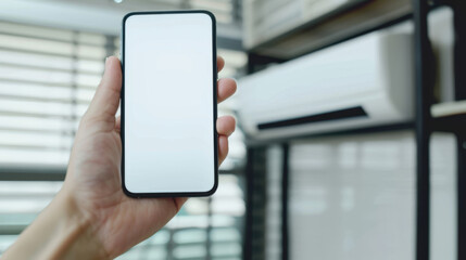 hand holding mobile phone with empty screen in front of air conditioning unit