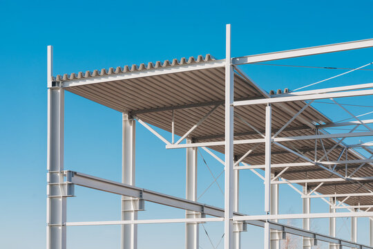 Modern Steel Frame Construction with Corrugated Roof Panels Against Clear Blue Sky