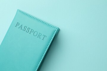 Passport in bright cover on light blue background, top view. Space for text