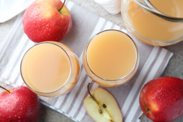 Refreshing apple juice in glasses, jug and fruits on grey textured table, flat lay