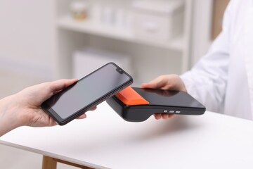 Woman paying with smartphone via terminal at counter indoors, closeup