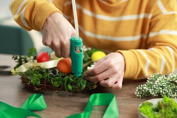 Woman with hot glue gun making craft at table indoors, closeup