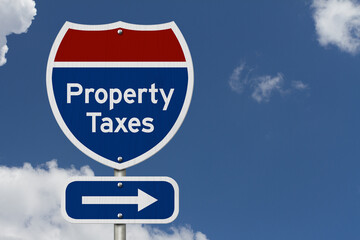  Property taxes road sign with arrow under a blue sky