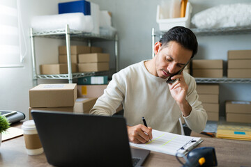 Entrepreneur multitasking in his small business store, taking notes and managing customer orders...