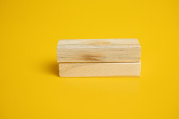 two wooden blocks arranged neatly on a solid yellow background.