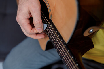 Guitarist on acoustic guitar playing melody. Close up musician instrument with pick in hand