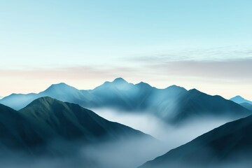 Fototapeta premium The mountains are covered in fog and the sky is a beautiful shade of blue. The scene is serene and peaceful, with the mountains towering over the landscape