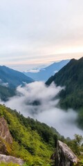 Fototapeta premium The mountains are covered in clouds and the sky is a mix of blue and orange. The scene is serene and peaceful, with the mountains providing a sense of calm and tranquility