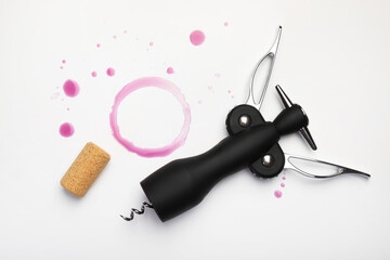 Wing corkscrew, cork and red wine stains on white background, top view