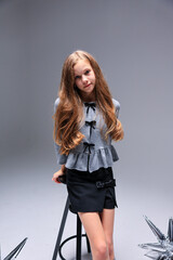 Fototapeta premium In a modern studio, a fashionable girl poses confidently, showcasing her chic style and elegance effortlessly