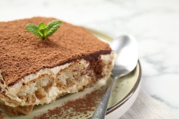Piece of tasty tiramisu on white marble table, closeup