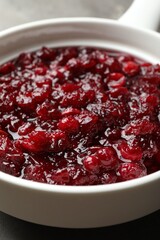 Tasty cranberry sauce in gravy boat on table, closeup