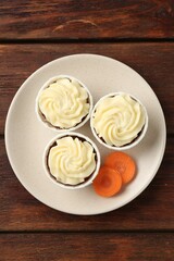 Delicious carrot muffins and fresh vegetable on wooden table, top view