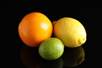 Fresh orange, lemon and lime on black mirror surface, closeup