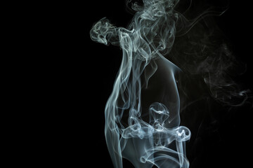 Delicate wisps of smoke swirling in the air against a dark background at night