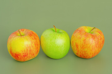 Two red and yellow apples and one green apple. Fruit, apples on a green background.
