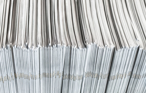 Newspaper, magazine or comic pile stacked horizontally on mainstream media newsstand. The publications contain information about news and current events. Fresh off the press.
